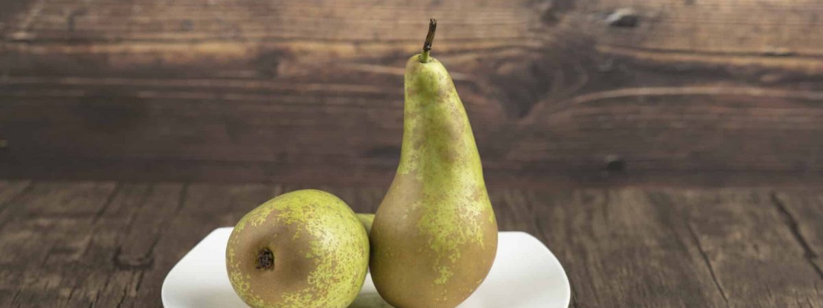White plate of delicious ripe pears on wooden surface. High quality photo